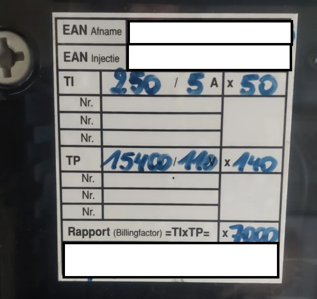 Het label op een industriële Fluvius-meter met de CT-verhouding 250/5 A maal 50 en de VT-verhouding 15400/110 V maal 140 met de hand bijgeschreven, en de factureringsfactor die daaruit volgt.